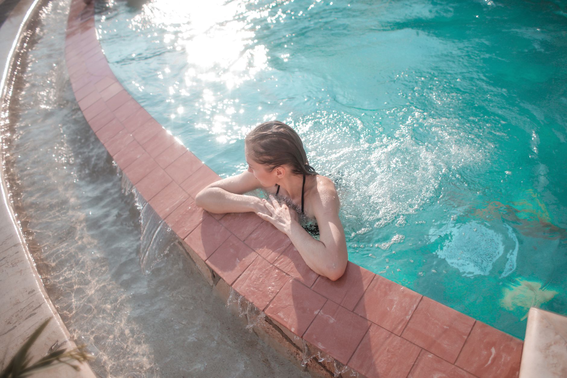 Person sitting chest deep in a metal cold plunge tub in a backyard