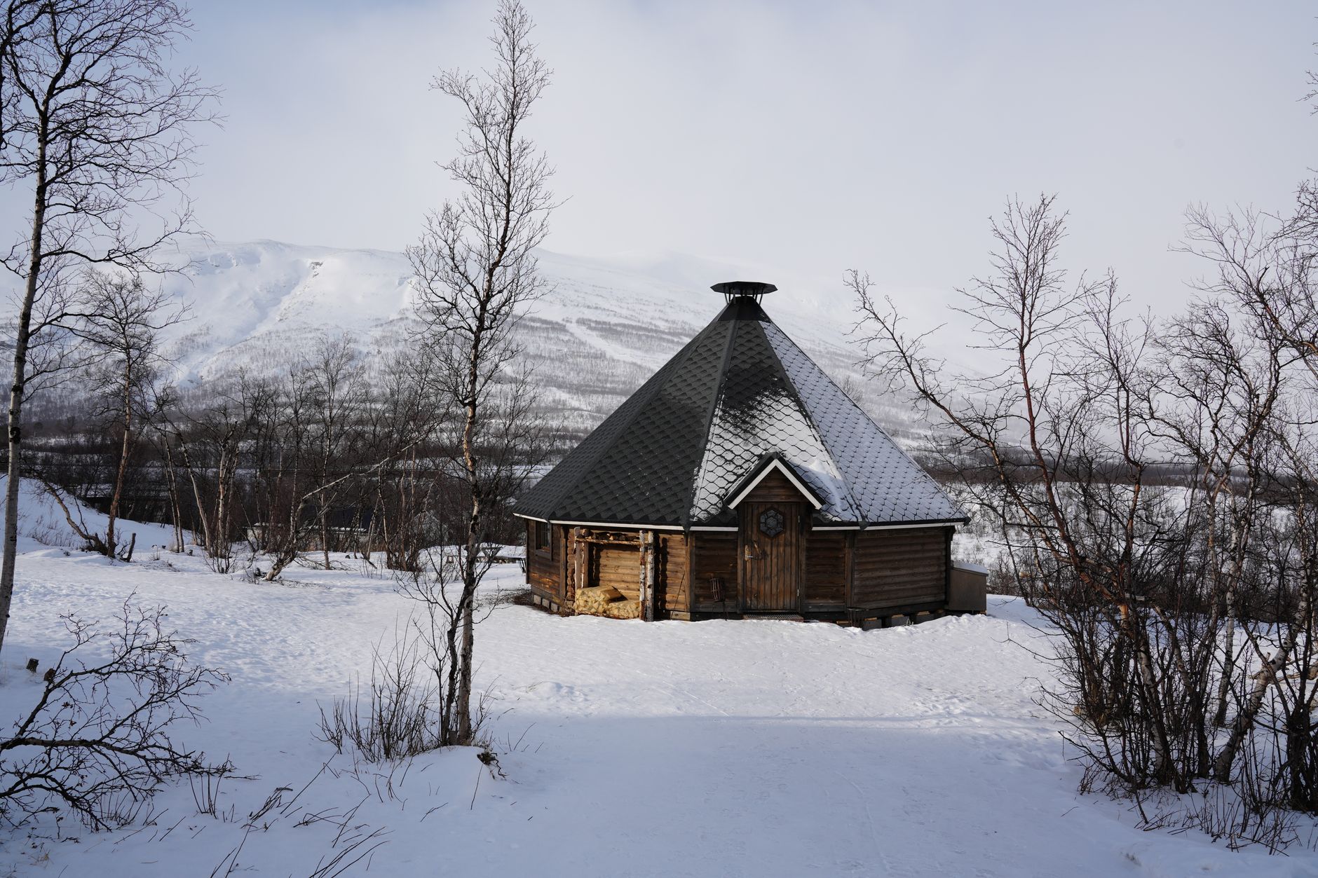Traditional wooden cabin sauna with chimney beside snowy trees